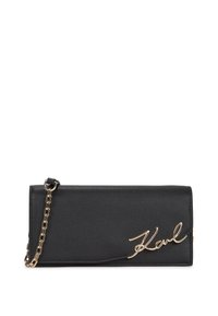 Black leather wallet with a gold chain strap, featuring a signature "Karl" logo in cursive on the front, smooth texture and sleek design.