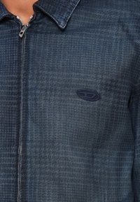 Tumši zilas džinsa jaka ar rūtainu rakstu. Ir rāvējslēdzēja aizdare un smalks izšūts logotips uz krūšdaļas. Klassiska apkakles dizains.