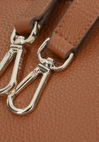 Pelle marrone testurizzata con due chiusure metalliche, dotata di hardware in argento lucido e cinture attaccate, che evidenzia un'eccellente lavorazione artigianale.