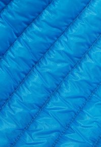 Blå quiltad tyg med en glansig, slät yta och diagonala sömmar för isolering. Lätt och kompakt design.