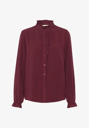 Bordowa bluzka z długim rękawem, z falbaniastego kołnierza i zapięciem na guziki z przodu. Posiada marszczone mankiety oraz gładką teksturę materiału.