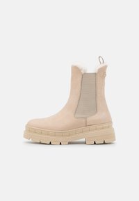 Beige ankle boots featuring a suede upper, elastic side panels, fluffy collar trim, and a chunky rubber sole with a textured finish.