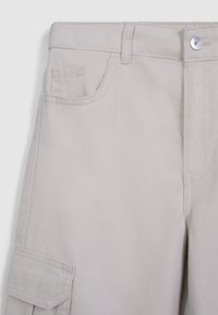 Pantalons cargo beiges avec une coupe droite, plusieurs poches et une fermeture à bouton. Fabriqués en tissu tissé résistant avec une texture lisse.