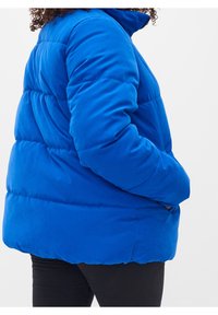 Blå pufferjakke med høj krave, quiltet tekstur og sidelommer, der har en løs pasform og blødt materiale til varme.