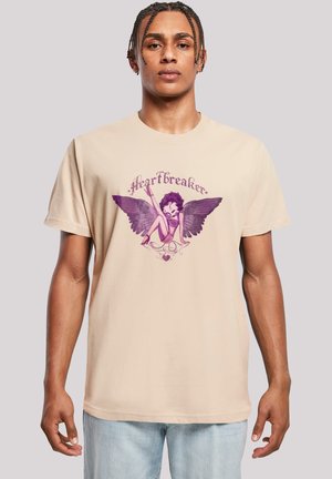 Beige Baumwoll-T-Shirt mit einer Illustration eines Charakters mit lilanen Flügeln und dem Text "#Heartbreaker" über dem Design.