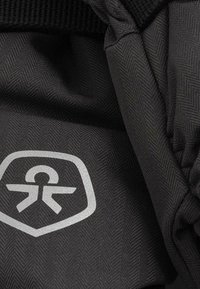 Czarna tkanina w wzór rybiej ości o gładkiej teksturze, z srebrnym logo w konturze tarczy i siateczkowymi detalami wzdłuż krawędzi.