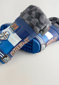 Blaue Gummislipper mit gesteppten grauen Oberteilen, die mit karierte Muster, Logos und Text versehen sind. Strukturierten Sohlen für Halt und Stabilität.
