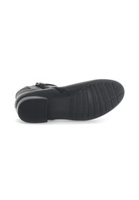 Zapato de cuero negro con un tacón bajo y una suela de goma texturizada. El diseño presenta una correa con herrajes metálicos. Ofrece un acabado suave.