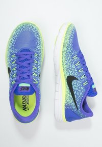 Chaussures de course Nike avec un dessus en maille violette présentant un motif en dégradé, un logo Swoosh noir et une semelle blanche rembourrée avec des accents verts.