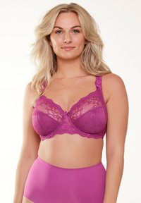 Paarse kanten beha met doorzichtige cups, gegolfde randen en een decoratieve strik tussen de cups; gestyled met eenvoudige, bijpassende hooggesneden slipjes.