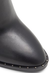 Black leather ankle boot with a pointed toe and silver studded accents along the sole. Smooth texture with a sleek design.
