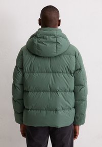 Green puffer jacket with a hood, featuring a quilted design and textured fabric. Sleeves are slightly padded, providing warmth and comfort.