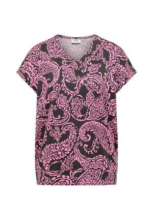 Femme de dos portant un t-shirt noir à manches courtes avec un motif paisley rose complexe et un pantalon beige clair avec des poches.