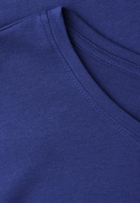 Niebieska tkanina o gładkiej fakturze, z okrągłym dekoltem i widocznymi szwami, podkreślająca rozciągliwość i jakość materiału.