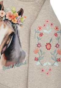 Felpa beige chiaro con una grafica di un cavallo con una corona di fiori e il testo "Miglior amico" in blu. Fiori ricamati colorati sulle maniche.