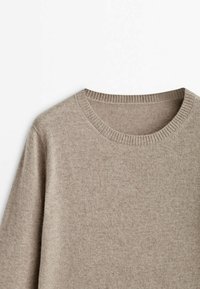 Pull en laine beige à col rond, vu de face en haut, mettant en valeur l'encolure côtelée et la texture douce du tricot.