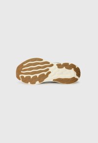 Sål med en bølgerdesign; har en cremefarvet skygge med brune gummidetaljer og teksturerede mønstre for bedre greb.