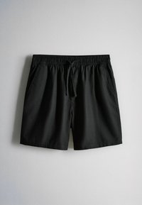 Shorts noirs décontractés avec taille élastique et cordon, dotés de poches latérales, posés à plat sur un fond gris clair.