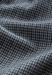 Tissu tissé présentant un motif pied-de-poule dans des nuances de gris et de noir, avec une texture douce et une apparence lisse et fluide.