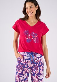 Camiseta de algodón roja con escote en V y gráfico de "JOY" en letras azules con contorno, combinada con pantalones de pijama de patrón azul y blanco con diseños de hojas.