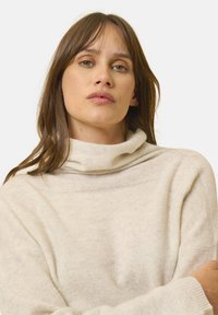 Maglione beige con collo a baldacchino, texture morbida, maniche larghe e vestibilità rilassata. Motivo a maglia visibile, adatto per un abbigliamento casual.