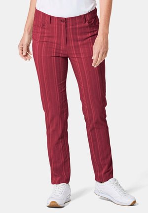 Pantalons à rayures rouges avec une texture lisse, dotés de poches avant et d'une fermeture à boutons. Portés avec des baskets blanches sur un fond neutre.