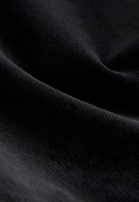 Black textured fabric with a soft, smooth finish and subtle ribbing details, displaying varying shades in light. Ideal for various textile applications.