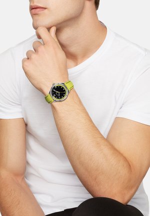 Orologio da polso con quadrante nero, ghiera argentata e cinturino verde lime vivace. Presenta marcature numeriche chiare e dettagli di cucitura in contrasto.