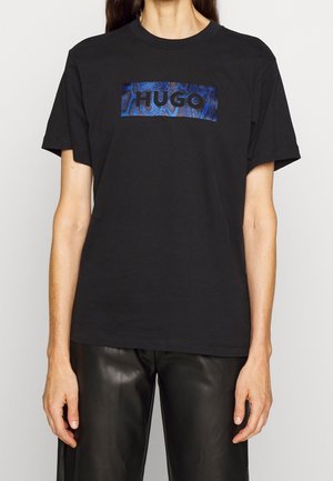 Camiseta de algodón negra con un gráfico rectangular de patrón de serpiente azul y "HUGO" en letras negras en negrita en el pecho.