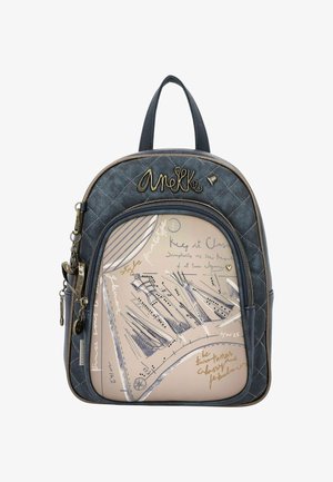 Zaino navy trapuntato con dettagli dorati; presenta una tasca anteriore beige chiaro con grafiche e testo scritto a mano. Due cinghie superiori.