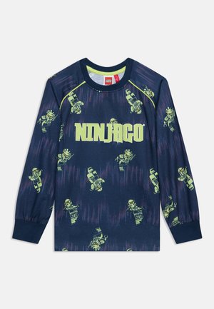 Chemise bleu foncé à manches longues avec des figurines LEGO Ninjago jaune-vert et le texte "NINJAGO" en grandes lettres jaune-vert sur la poitrine.