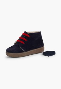 Scarpe alte in suede blu navy con lacci rossi, suola in gomma e dettagli marroni chiari. Include un ulteriore lacci di ricambio blu navy.
