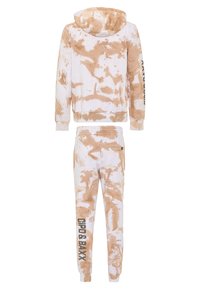 Hooded, tie-dye sweatshirt and matching pants in cream and light brown. Features ribbed cuffs, side pockets, and logo detail on sleeve and pant leg.