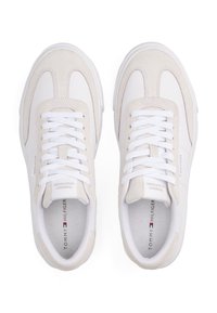 Ein Paar weiße und beige Tommy Hilfiger Sneaker mit weißen Schnürsenkeln, von oben auf einem weißen Hintergrund betrachtet.