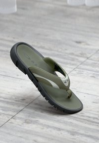 Chancla de color verde y blanco con suela texturizada, plantilla suave y detalles de logo. Presenta un pronunciado separador de dedos y un diseño ligero.