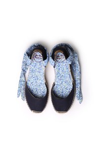 Parte superior de tela floral azul con puntera y talón de lona marina. Estilo espadrille con ribete de yute trenzado. Tiras de tela ajustables. Suela plana.