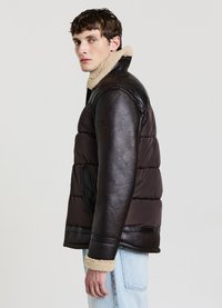 Doudoune marron avec un empiècement en cuir noir, un col en fourrure, des poches zippées et des poignets côtelés. Texture lisse avec un design rembourré.