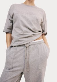 Lichtgrijze oversized t-shirt met de tekst "SUNDAY" en bijpassende grijze joggingbroek met een elastische tailleband en zijzakken.
