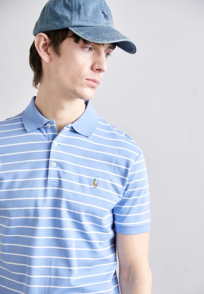 Γαλάζια ριγέ πόλο μπλούζα με κοντά μανίκια και γιακά, με μικρό κεντημένο λογότυπο στο στήθος. Τζην καπέλο μπέιζμπολ.