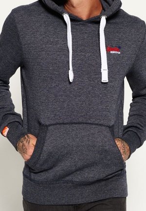 Sudadera gris oscuro hecha de tela suave, con un bolsillo delantero, cordones blancos y un pequeño logotipo en el pecho. Puños de punto texturizado.
