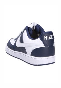 Sneaker in pelle bianca e blu navy con punta rotonda, collare imbottito, lacci bianchi e logo Nike sul tallone e sul lato. Suola in gomma.