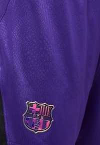 Μωβ ύφασμα με λαμπερό έμβλημα της FC Barcelona που διαθέτει κόκκινες, μπλε και μαύρες ρίγες και ένα στυλιζαρισμένο έμβλημα ποδοσφαίρου.