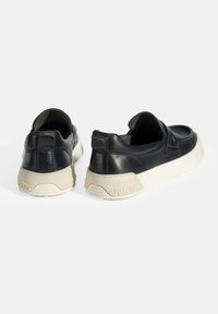 Donkerblauwe leren schoenen met een lage achterkant, voorzien van een dikke crèmekleurige rubberen zool. Eenvoudig ontwerp met een gladde textuur en minimale accenten.