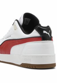 Bijela tenisica s crvenim i crnim akcentima, od kože i sintetičkih materijala, s Puma logotipom na peti, glatke teksture i gumenim potplatom.