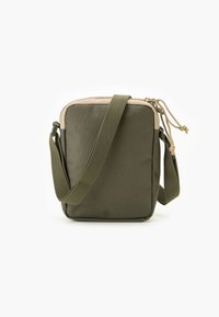 Žalios spalvos medžiaginė rankinė per petį, stačiakampio formos, su smėlio spalvos detalėmis, užtrauktuku ir reguliuojama dirželiu. Paviršius lygus.