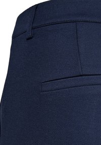 Donkerblauwe broek met een gestructureerde stof, smalle pasvorm en een enkele achterzak met subtiele naaddetails.
