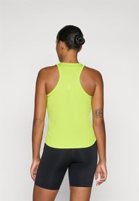 Lys neongrøn atletisk tanktop med racerback-design, glat tekstur og hvide accentdetaljer på ryggen, parret med sorte shorts.