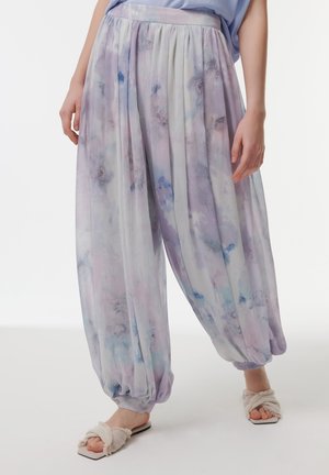 Lichte, luchtige lavendelkleurige harem pants met een aquarelpatroon, gathered enkels en een elastische tailleband. Gecombineerd met zachte, geschulpte sandalen.