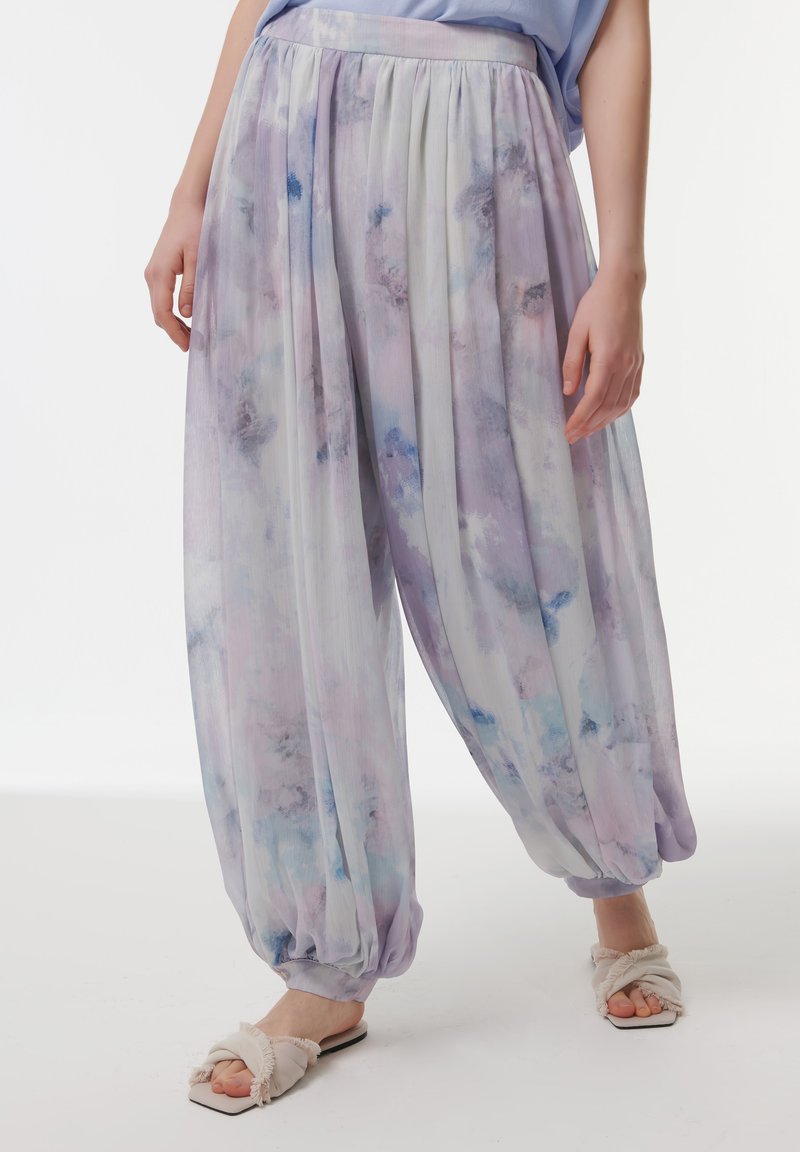 Lichte, luchtige lavendelkleurige harem pants met een aquarelpatroon, gathered enkels en een elastische tailleband. Gecombineerd met zachte, geschulpte sandalen.