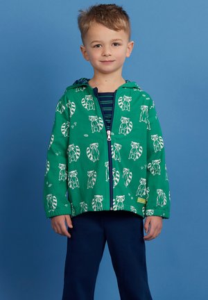 Green hooded jacket with white raccoon patterns, zip front, elastic cuffs, and hem, paired with a navy striped shirt and pants.